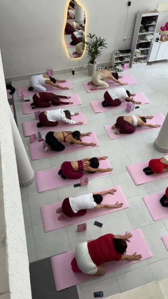 Vista de cima das alunas em posição de alongamento sobre tapetes rosa no Pilates Day